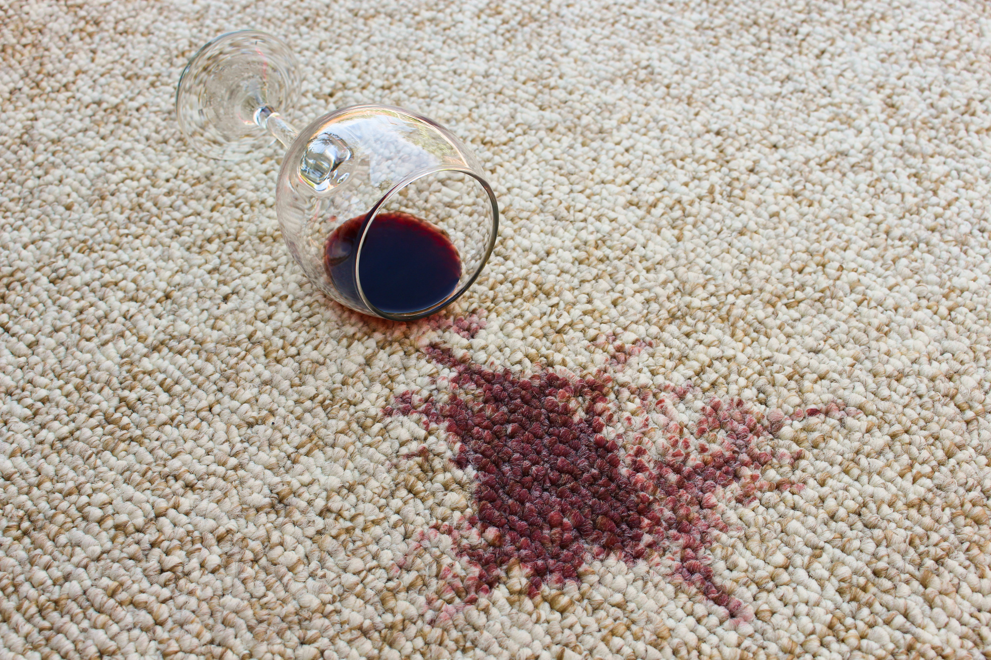 Glass of wine spilt causing wine stains on carpet